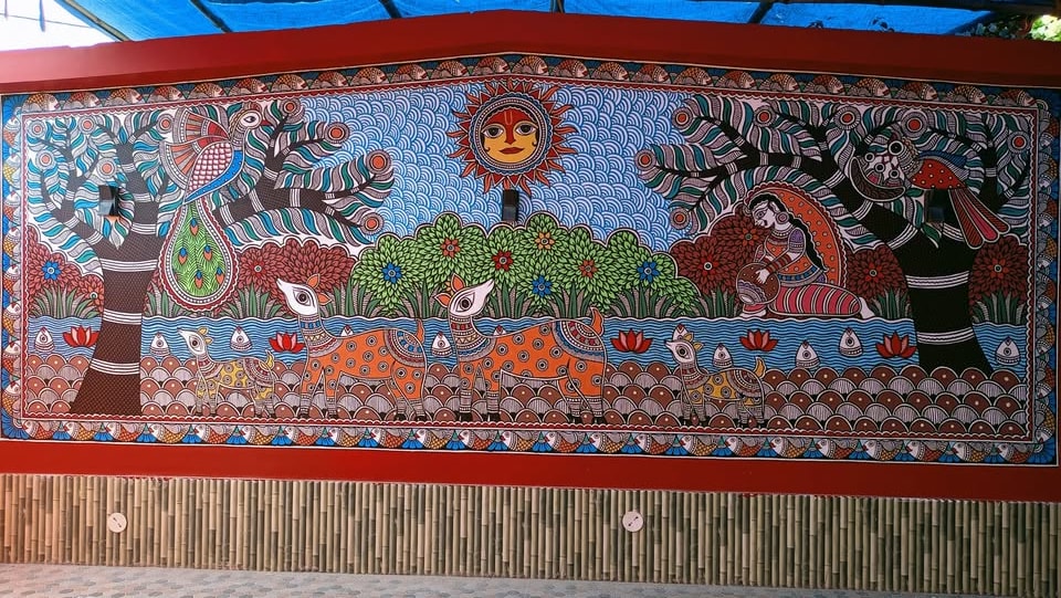 Grand Mithila mural — deer, trees of life and the sun across a full outdoor wall